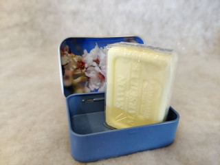 Savon de Marseille de la marque Esprit Provence à l'amande douce dans sa jolie boîte avec image de fleurs d'amandier. La boîte est bleue posée sur une surface blanche qui fait ressortir sa couleur éclatante