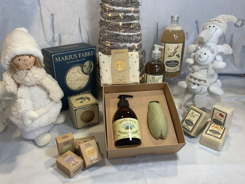 Les produits de la marque Marius Fabre sont élégamment posés sur une table décorée pour Noël. Savons, coffrets cadeaux et pochette de voyage sont en vente à l'Office de Tourisme de martigues 