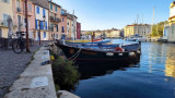 Ein Spaziergang am See Miroir aux Oiseaux mit seinen traditionellen Booten in der Altstadt von Martigues. Authentische Kulisse mit farbenfrohen Fassaden und Kopfsteinpflasterstraße