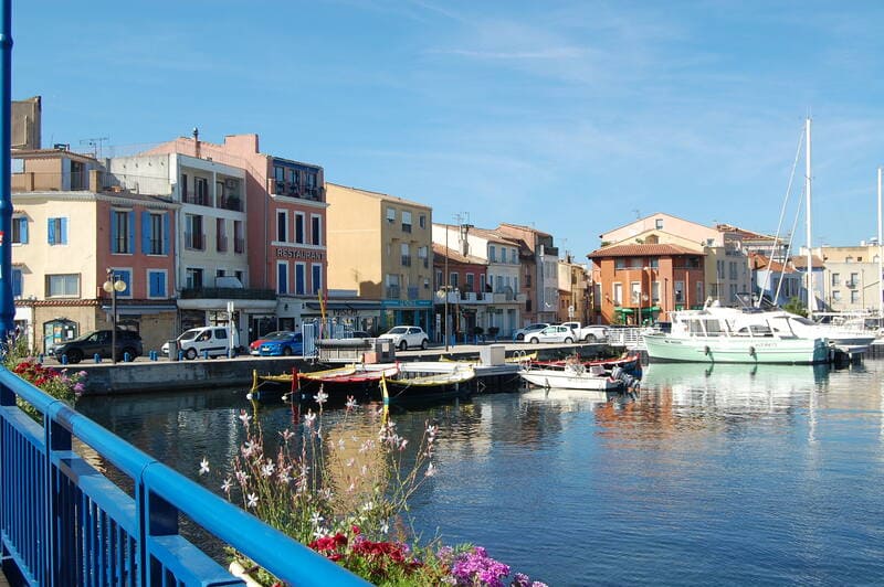 Photo prise depuis le pont bleu de Martigues avec vue sur les façades colorées et les barques traditionnelles des rameurs vénitiens de Martigues - © Otmartigues / MarieB