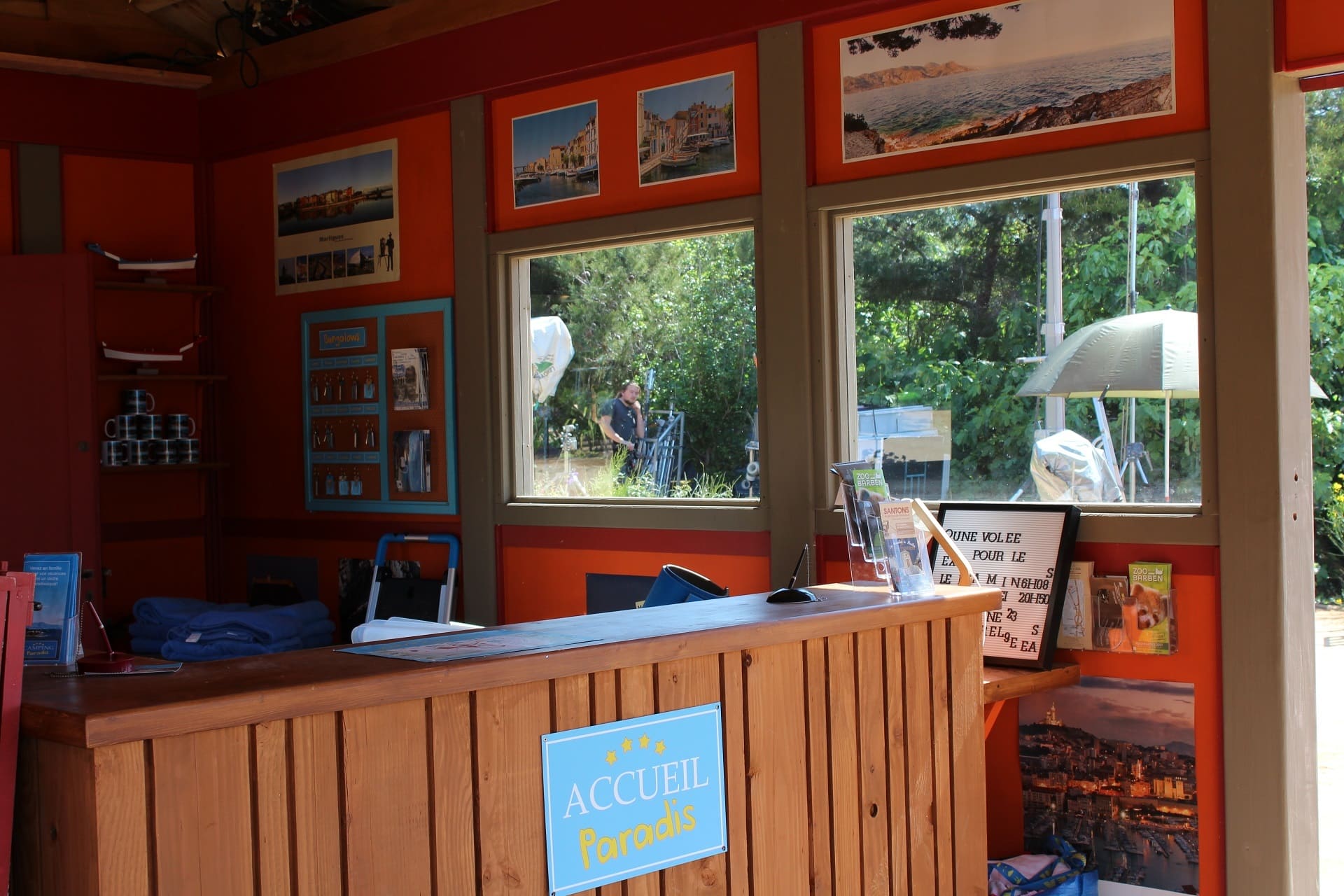 Intérieur de l'accueil Camping Paradis où Tom et Elsa reçoivent les touristes du camping dès leur arrivée. Aménagés avec des photos et des cadres, le lieu est vivant et habité - © Otmartigues / ElodieM