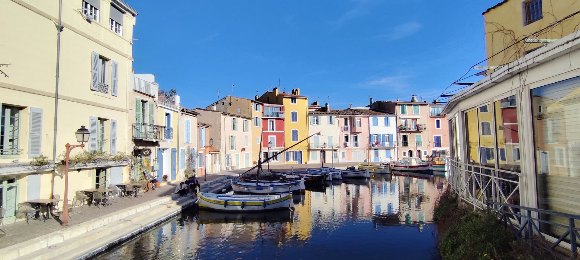 Plan d'eau du Miroir aux Oiseaux avec ses façades colorées aux couleurs pastels et les barques traditionnelles amarrés au quai. Photo prise depuis un pont avec vue d'ensemble sous un ciel bleu - © Otmartigues / MyriamF
