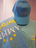 Blue Camping Paradis cap worn by a mannequin, featuring a branded towel on the shoulder and a blue polo
