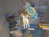 Camping Paradis flip-flop keychain, hanging against a colorful background