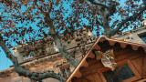 Artistic photo of a wooden Christmas chalet with a winter tree and ocher building in the background, under a clear blue sky