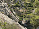 La photo est prise sur les hauteurs en plongée. On voit le groupe de participants à l'initiation d'escalade attendre leur tour. Une personne gravi la calanque pour atteindre le sommet