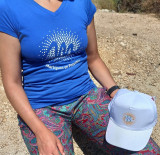 Tee-shirt femme bleu de la Gamme Soleil, logo de l'Office de Tourisme en blanc au centre, avec une casquette blanche de la même marque posée sur le genou sur la seconde photo
