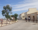 Le centre du village de Carro. Deux personnes font du vélo. Des arbres sont sur la gauche. Des maisons sont bâties sur la droite.