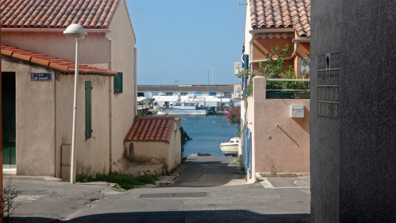 Au sein du village de Carro, les maisons aux allures provençales sont basses. Un descente de la rue mène vers le port où on voit l'eau et les bateaux amarrés.