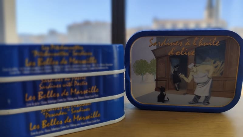 Dose Sardinen in Olivenöl von Ferrigno. Eine Grafik zeigt einen Fischhändler, der eine fischliebende schwarze Katze zurechtweist.