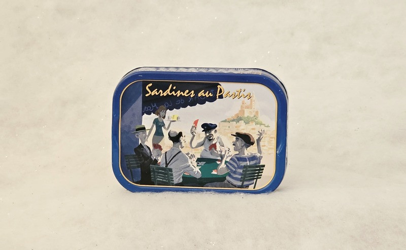Lata de sardinas en pastis de Ferrigno, Port-Saint-Louis-du-Rhône. La caja muestra jugadores de cartas sentados en un bar bajo plátanos, la buena vida en la Provenza. - © Otmartigues / MarianneB Sardinas enlatadas en pastis de la marca Ferrigno, una conservera de Port-Saint-Louis-du-Rhône, cerca de Martigues. Disponibles en la Oficina de Turismo de Martigues.