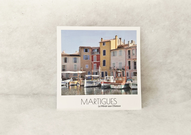 Postal cuadrada que muestra una pintoresca vista del Espejo de los Pájaros con sus barcos tradicionales y casas coloridas, en el distrito de Île, Martigues. - © Otmartigues / MarianneB Postal estilo Polaroid del Espejo de los Pájaros en Martigues, la Venecia provenzal. Vista de barcos pesqueros tradicionales (pointus) amarrados en el canal, rodeados de casas de pescadores con fachad