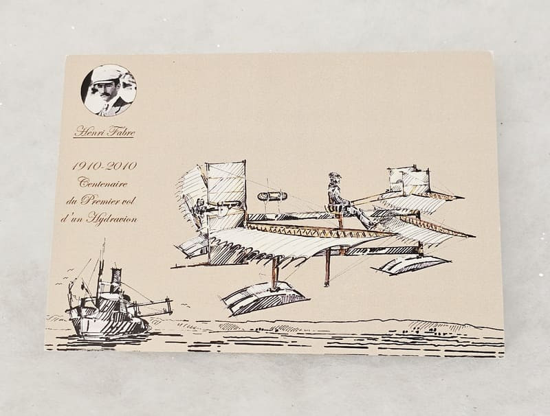 Carte postale représentant un dessin concept art d'un hydravion, mettant en avant des lignes futuristes et un design élégant. - © Otmartigues / MyriamF Carte postale en référence au premier vol d'hydravion sur l'étang de Berre à Martigues. Carte postale en vente à l'Office de Tourisme de Martigus