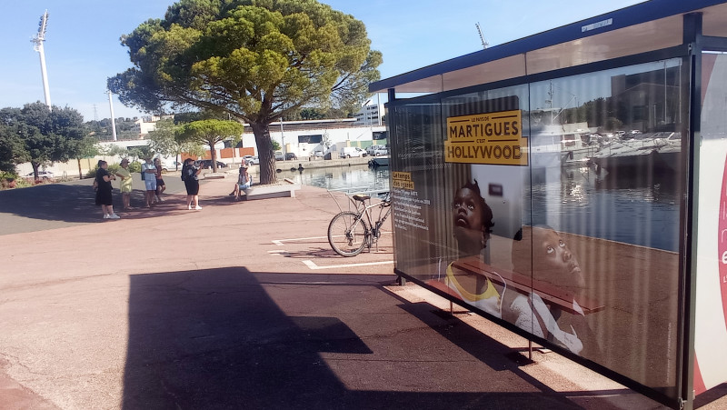 Un abri bus est habillé d'affiches publicitaires en référence à des films ayant été tournés à Martigues. Une phrase indique 