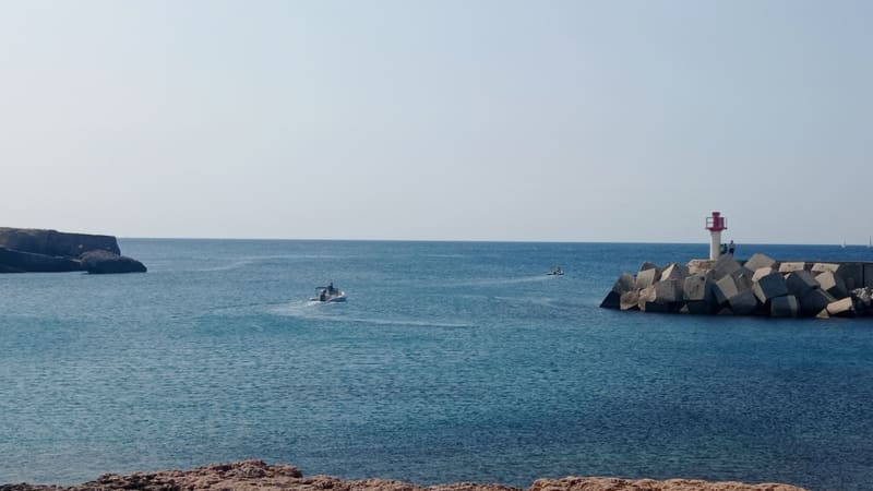 Carro Port and its lighthouse facing the beach.