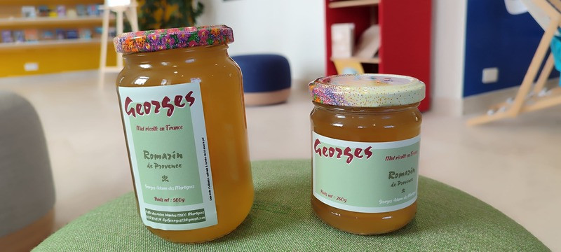250g jar of honey from Ruchers de Georges, highlighting the rosemary honey, placed on a wooden table