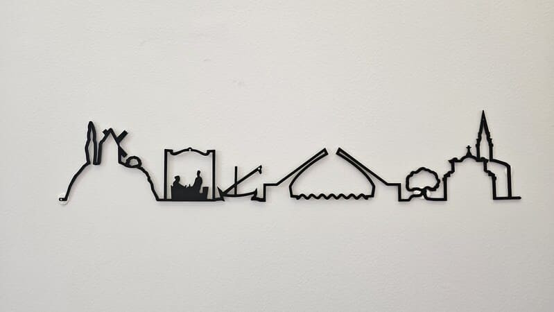 Ligne en métal de couleur sombre qui reprend les sites touristiques de Martigues : chapelles, églises, barques et ponts de Martigues - © Otmartigues / MarianneB Ligne d'horizon en métal de décoration reprenant les symboles de Martigues : églises, chapelles, ponts et barques du Miroir aux Oiseaux. Une ligne spécialement créé pour l'Office de Tourisme de Martigues