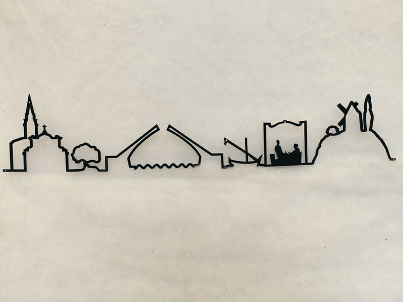 Línea decorativa metálica con forma de horizonte que presenta los símbolos de Martigues: iglesias, capillas, puentes y barcos del Miroir aux Oiseaux (Espejo de Pájaros). Una línea creada especialmente