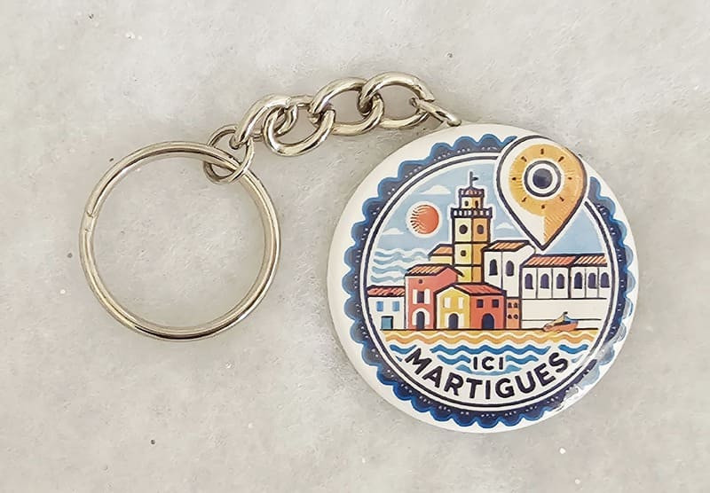 Keyring to attach to your bag or belt featuring a design of downtown Martigues. Cartoon style. Template from the ICI Martigues range, exclusively available at the Martigues Tourist Office.