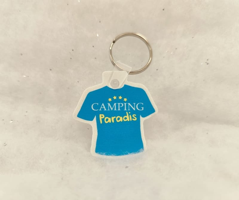 Porte-clé en forme de tee-shirt aux couleurs de Camping Paradis - © Otmartigues / MyriamF Porte-clé en forme de tee-shirt aux couleurs de la série Camping Paradis. Un produit de la collection Camping Paradis en vente à l'Office de Tourisme de Martigues