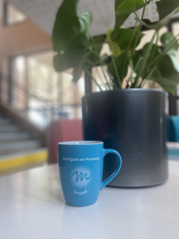Elegant blue mug placed on a gray table, with a plant in the background and a blurred staircase adding depth to the scene