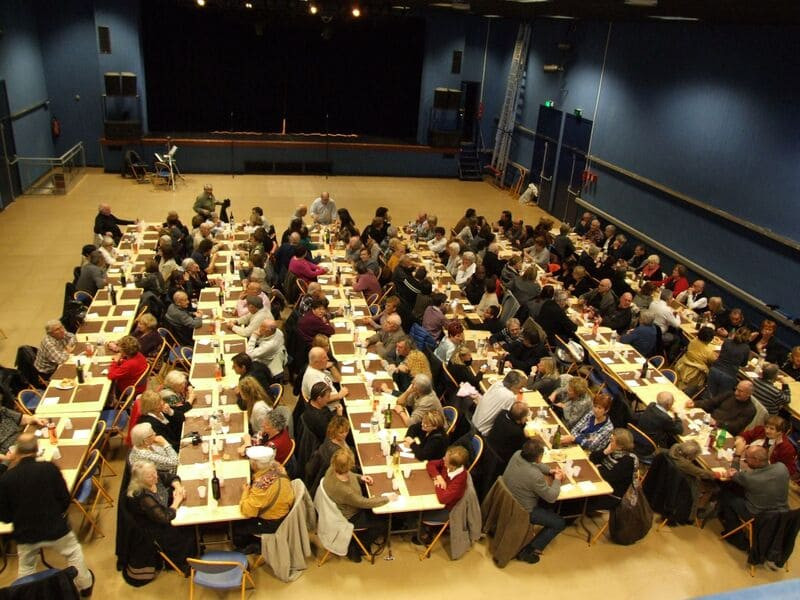 Overhead view of participants enjoying a traditional meal before the Pastorale Maurel show in Martigues, with rows of tables in a convivial atmosphere