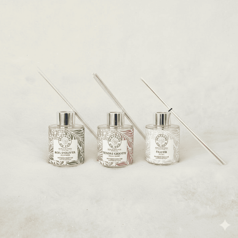 Tres ramos aromáticos dispuestos uno junto al otro, cada uno con una etiqueta de color diferente que indica su fragancia. Sus tallos de madera descansan sobre el ramo. - © Crédit photo : Otmartigues-MarianneB / Montage : IA Gemini Ramos aromáticos con aromas provenzales: higo, madera de olivo y guinda, de la marca Senteurs du Sud. Con difusor de madera, disponibles para su compra en la Oficina de Turismo de Martigues.