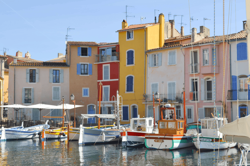 Genießen Sie den bezaubernden Anblick des Miroir aux Oiseaux und seiner farbenfrohen Häuser. Erfahren Sie mehr über die Geschichte hinter diesen Farben während der Stadtführung, die vom Fremdenverkehrsamt Martigues angeboten wird.