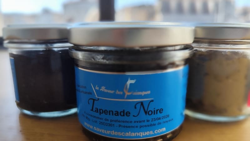 Glas schwarze Tapenade mit blauem Etikett mit dem Hinweis auf „Saveur des Calanques“. Streichfett erhältlich im Fremdenverkehrsamt Martigues in Zusammenarbeit mit der Konservenfabrik Lou Mujou in Port