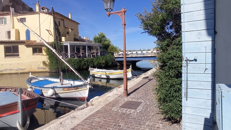 Barques traditionnelles amarrées sur le quai du Miroir aux Oiseaux à Martigues. Une partie de la photo représente l'entrée du restaurant Le Miroir - © Otmartigues / MyriamF
