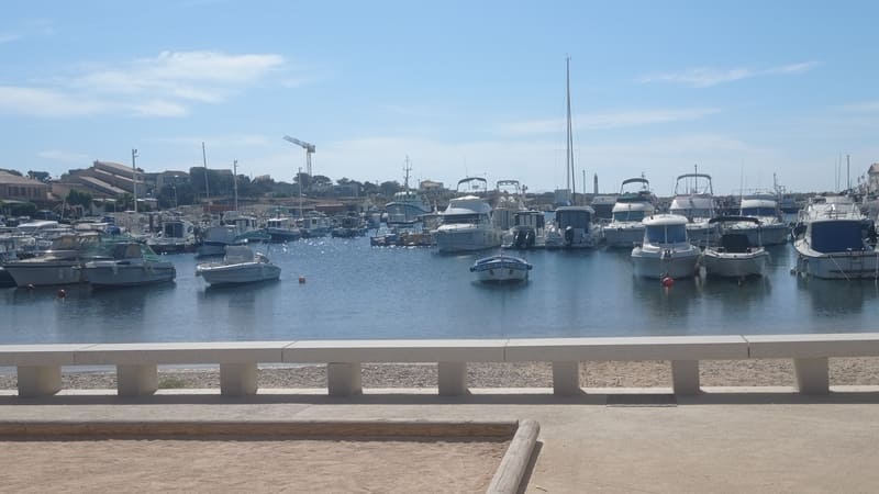 Der ausgebaute Kai des Hafens von Carro und die im Meer vertäuten Motorboote. Die Boote liegen in einer Reihe, das Wasser ist ruhig, im Hintergrund sind die Trawler zu sehen. - © Otmartigues / MyriamF