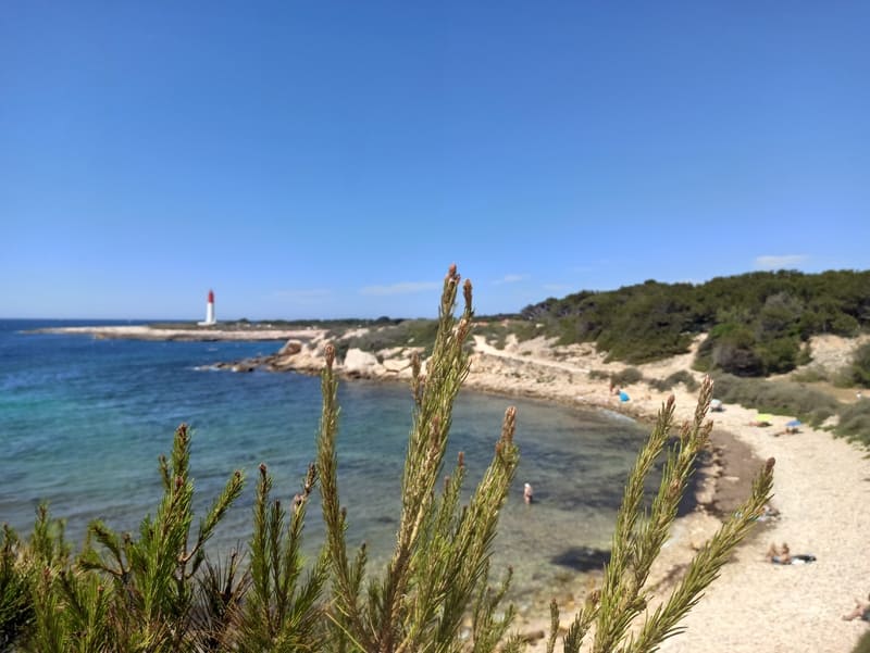 Sentier du littoral de Martigues qui traverse les criques, les plages et borde la mer méditerranée. Le phare de La Couronne est reconnaissable au loin. Une lagune de sable permet aux touristes de s'y poser et de se baigner - © Otmartigues / KarimK