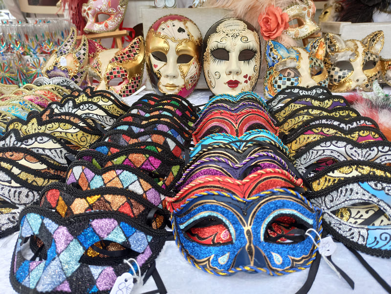 Máscaras coloridas que cubren los ojos o el rostro entero se exhiben en cascada en un puesto del mercado italiano de Martigues. - © Otmartigues / KarimK