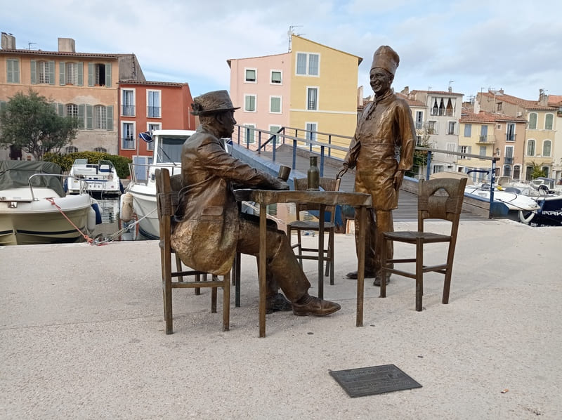 Statues de Bourvil et Fernandel, acteurs français. En hommage au film La Cuisine au Beurre tourné à Martigues. De l'autre côté du canal, la maison en chapeau de gendarme ayant servi de décor au film, lieu de tournage principal à Martigues - © Otmartigues / MyriamF