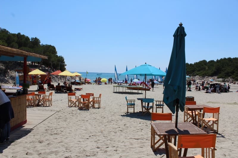 Tournage de la série Camping Paradis à Martigues sur la plage. Des tables et parasols sont au premier plan en référence au bar sur la plage dans la série. Au loin, la mer méditerranée est visible - © Otmartigues / ElodieM