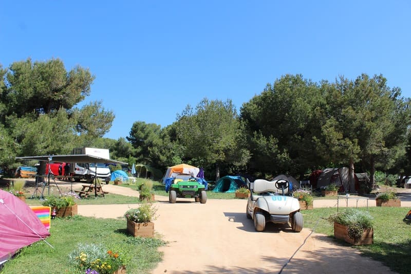 Plusieurs voiturettes dont la voiturette officielle de Tom dans la série télévisée Camping Paradis. Elles sont arrêtées dans les allées du camping à proximité de tentes posées dans l'herbe - © Otmartigues / ElodieM
