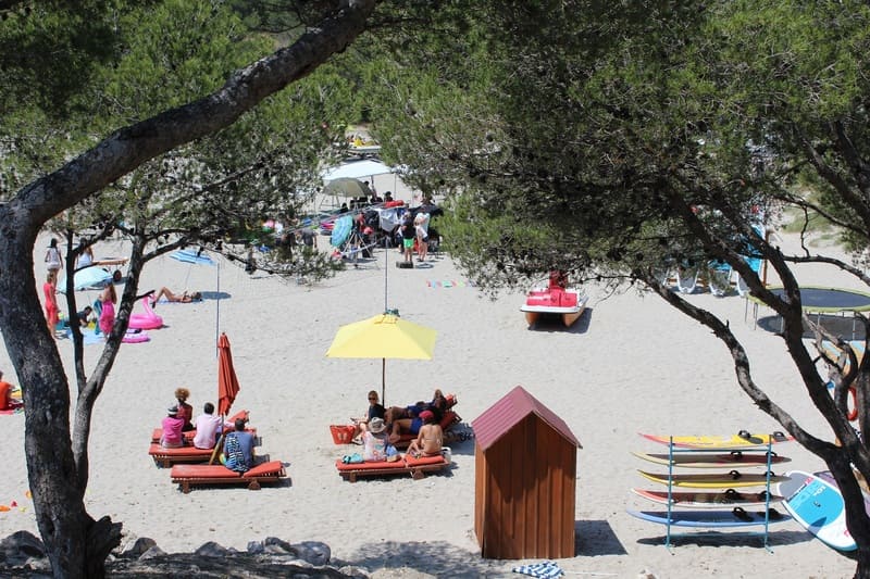 Transats et parasols avec cabines de plage et planches de paddle à la location sont installés sur la plage de la Saulce à Martigues. Ayant servi au tournage de la série Camping Paradis à Martigues - © Otmartigues / ElodieM